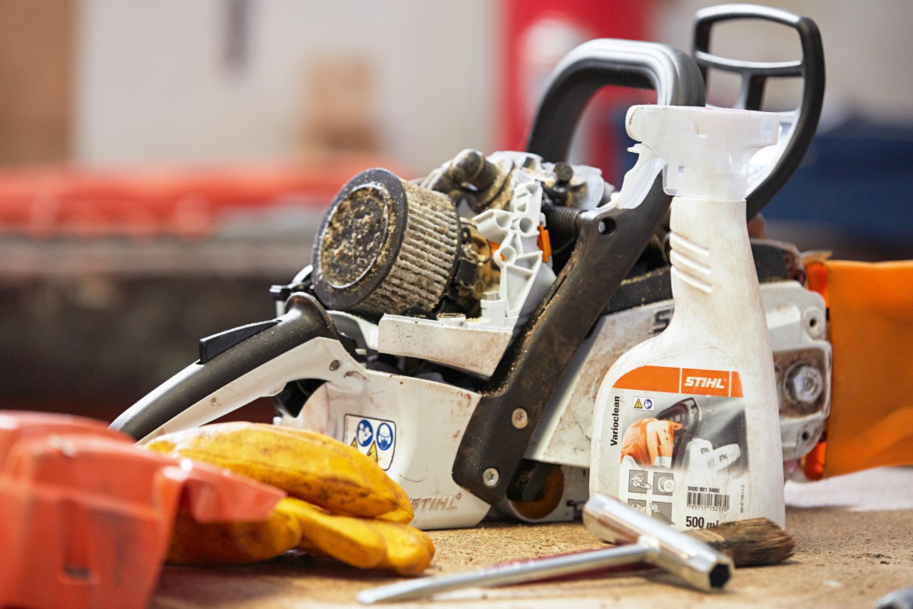 Producto para la limpieza de motosierras STIHL Varioclean al lado de una motosierra en un banco de trabajo