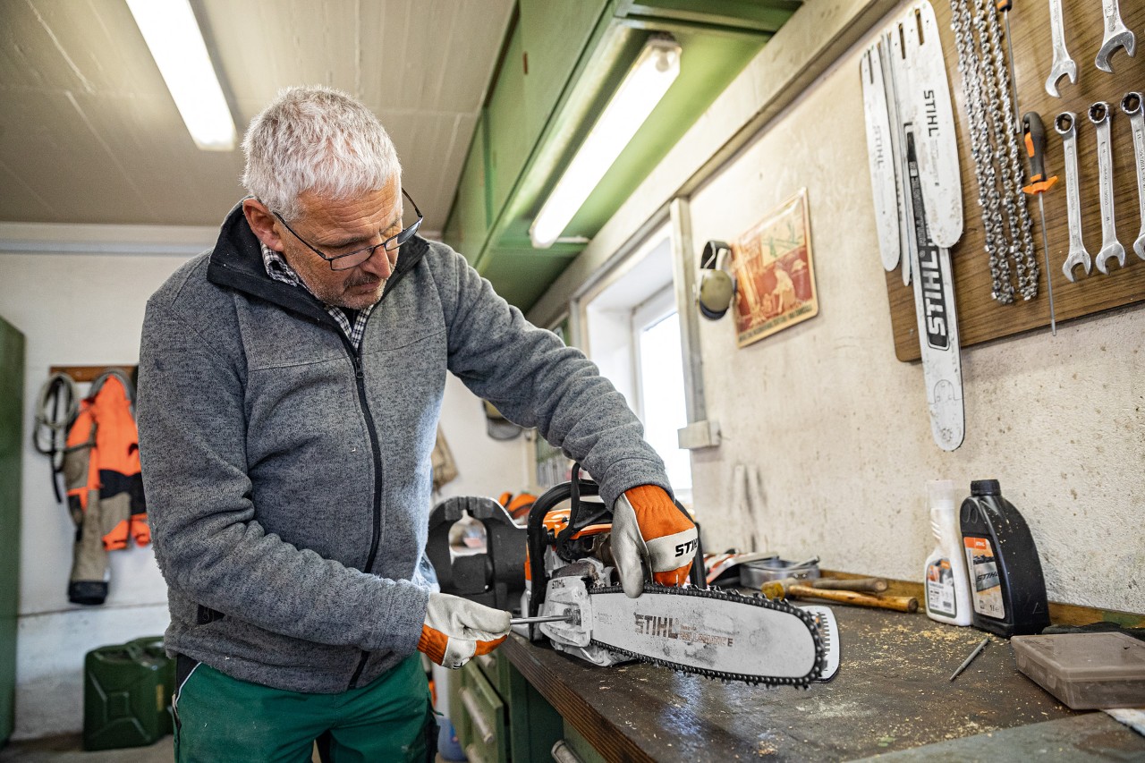 Un hombre en el proceso de tensar una cadena de motosierra STIHL en un taller