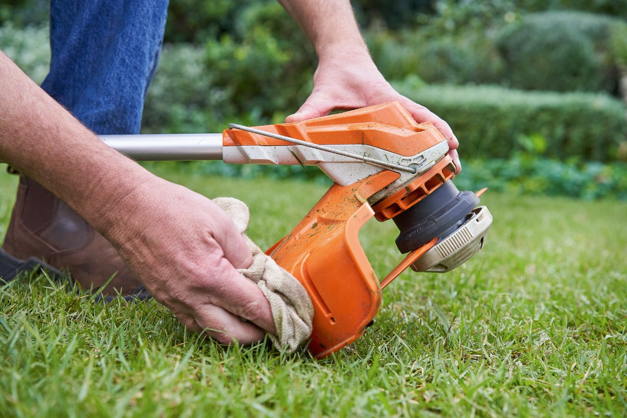 Una persona limpia con un paño húmedo la protección de una desbrozadora STIHL