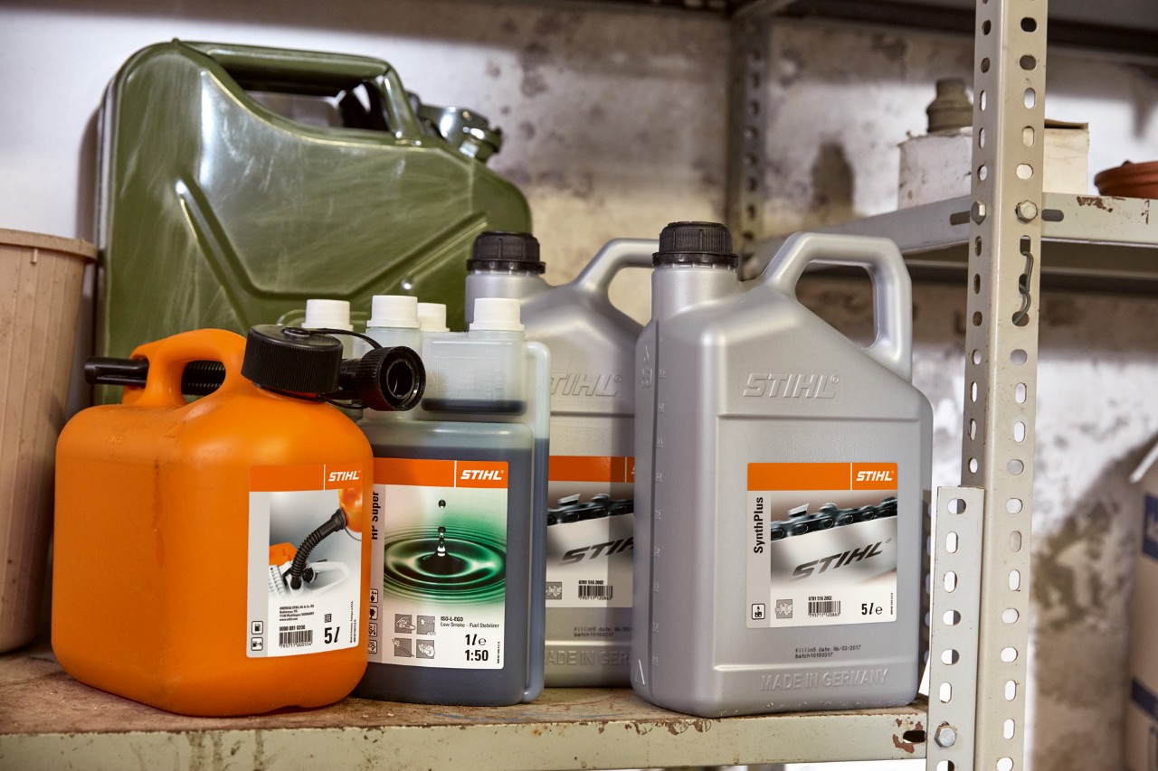 Un bidón grande de acero, una botella de aceite para motor de 2 tiempos STIHL HP Super y un bidón de mezcla