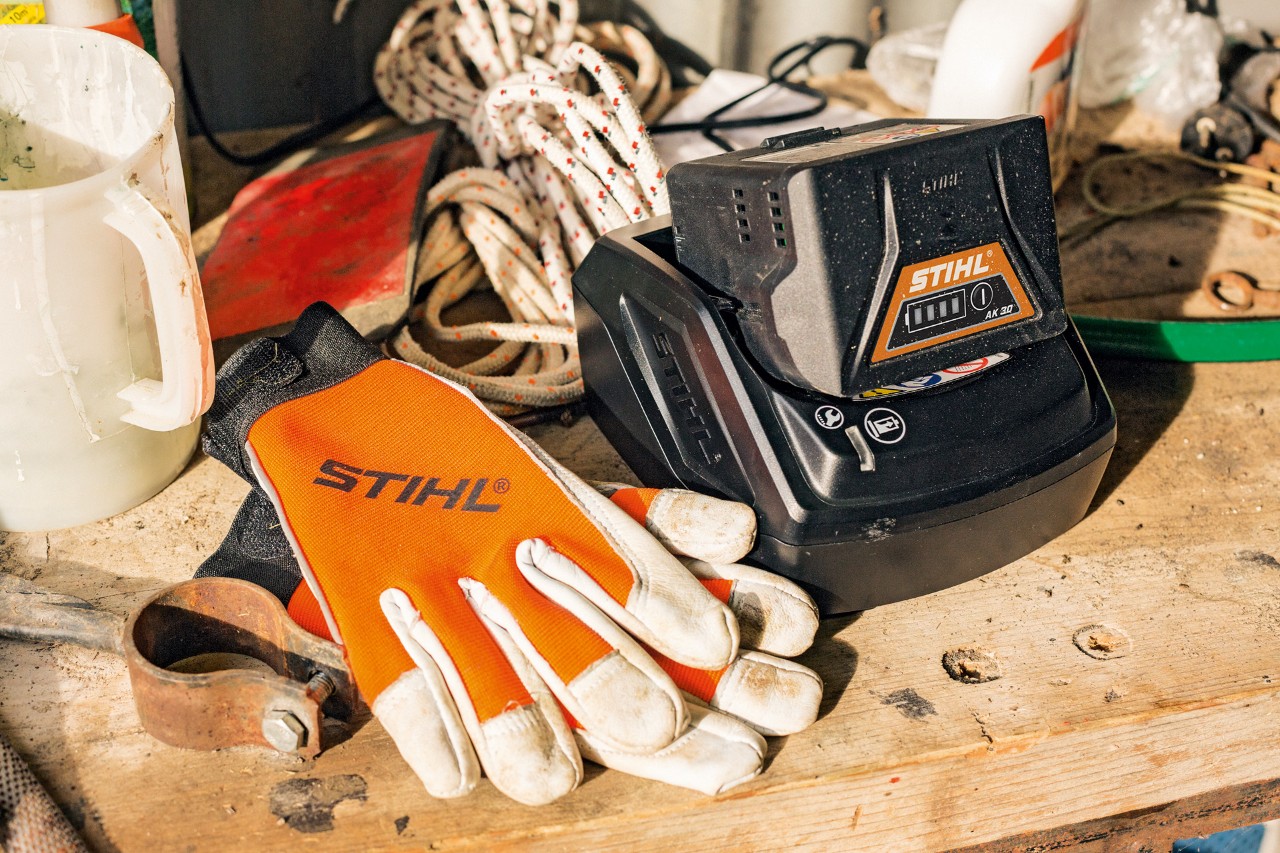 Unas baterías de iones de litio de la serie AK se cargan junto con unos guantes y unas herramientas de trabajo STIHL
