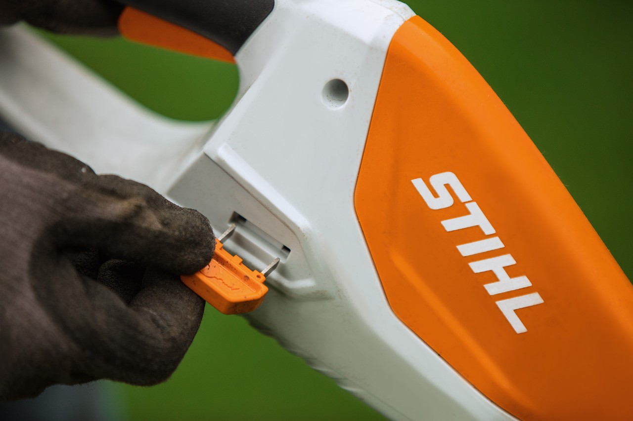 Primer plano de la clave de activación de un cortabordes STIHL con batería ion litio en funcionamiento pleno