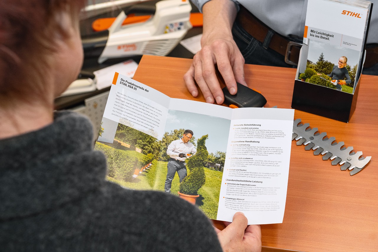 Una persona observa las ventajas del producto STIHL HSA 25 en un folleto