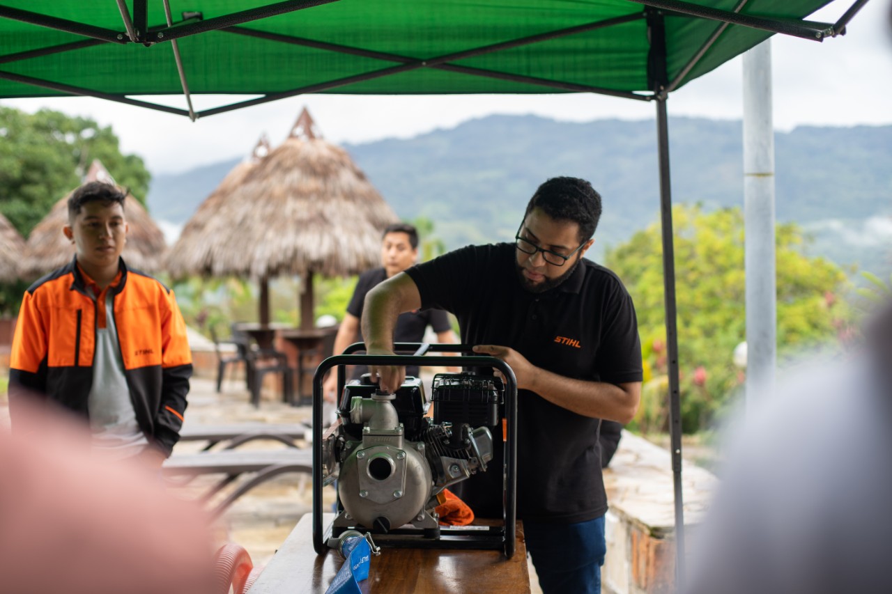 Un distribuidor STIHL coloca un robot cortacésped STIHL iMOW en su estación de carga en un jardín