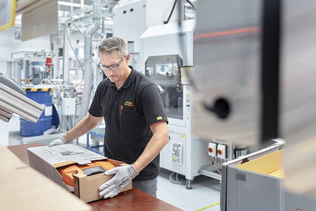 Un empleado de la producción de baterías empaqueta una máquina de batería STIHL en una caja de cartón 