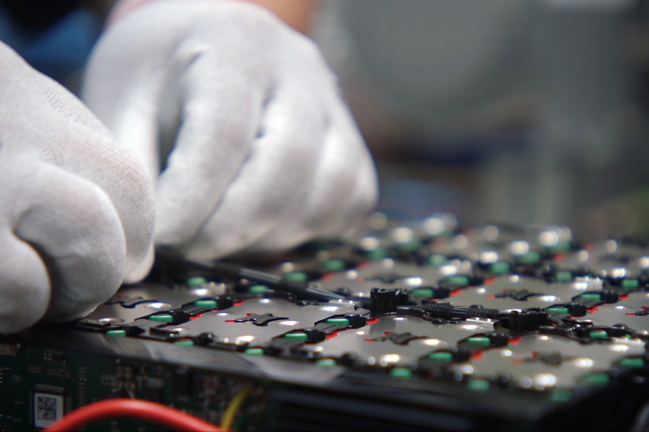 Primer plano de una persona con guantes de trabajo montando sensores en la batería
